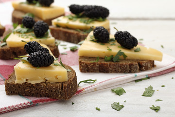 wood background sandwich with cheese and mulberry