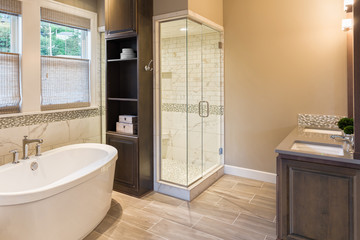 Large furnished bathroom in luxury home with tile floor, fancy cabinets, large mirror, shower, and bathtub