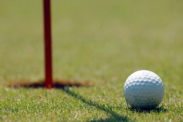 Golf player at the putting green hitting ball into a hole