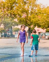 Fototapeta na wymiar Girl and boy are enjoying fountain