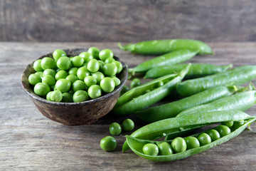 Green peas in wooden bowl on wood
