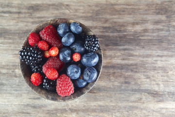 Assorted berries in bowl on wood