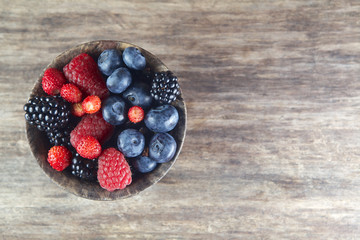 Assorted berries in bowl on wood