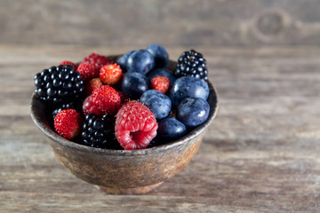 Assorted berries in bowl on wood