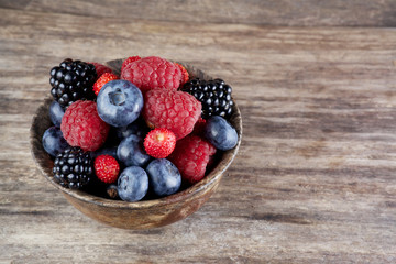 Assorted berries in bowl on wood