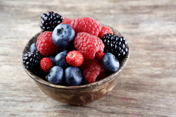 Assorted berries in bowl on wood