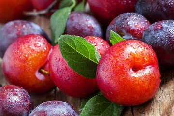 Ripe blue and red plums on old wooden background, selective focu