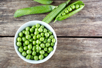 Green peas in wooden bowl on wood