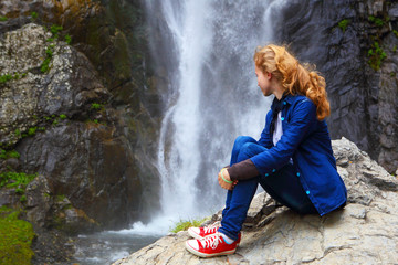 The blonde girl at the waterfall in the mountains.Travel and leisure on holiday.
