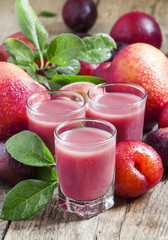 Delicious fresh juice of red and blue sweet plums and peach in a