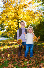 Sister with brother with autumn leaves in the park