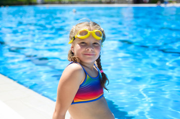 Smiling little girl in swimming goggles in the swimming pool