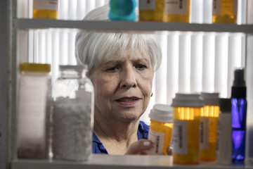 A mature woman grabbing one of her many medications