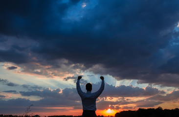 businessman standing on field to face the sunset