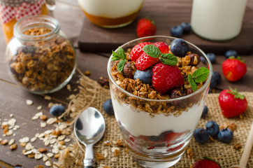 Yogurt with baked granola and berries in small glass