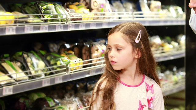 Father and daughter picking out salad in supermarket