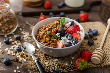 Yogurt with baked granola and berries in small bowl - obrazy, fototapety, plakaty