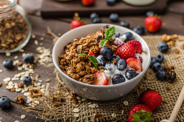 Yogurt with baked granola and berries in small bowl