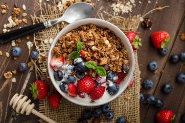 Yogurt with baked granola and berries in small bowl - obrazy, fototapety, plakaty