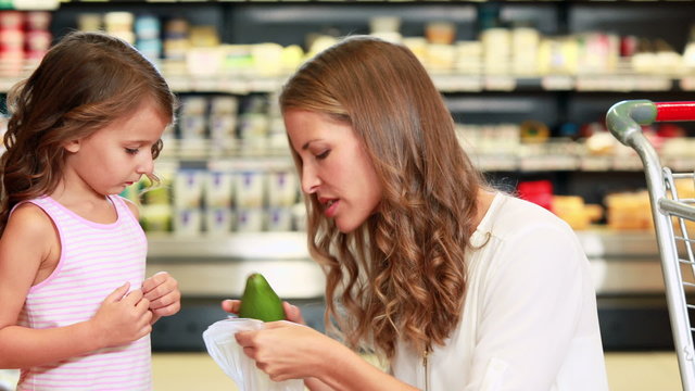 Mother and daughter picking out pepper in supermarket