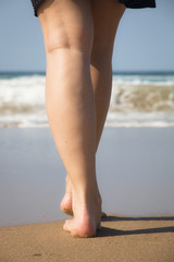 The legs and feet of a girl walking towards the indian ocean in Ponto Do Ouro, Mozambique

