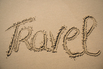 The word travel written in the sand on a beach in Mozambique
