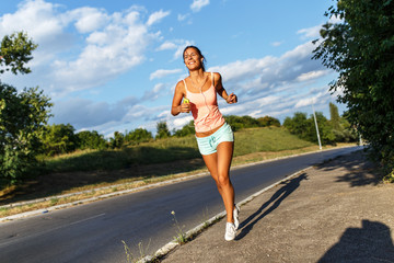 Female jogger running by the road.Sunny day.