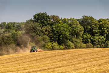 Tractor harvester working in rapeseed field in summer time
