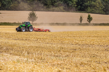 Obraz premium Tractor harvester working in rapeseed field in summer time 