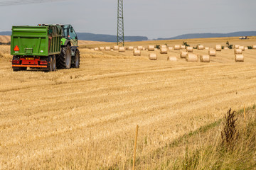 Obraz premium Truck preparing to load hay bales on a field during harvest time 