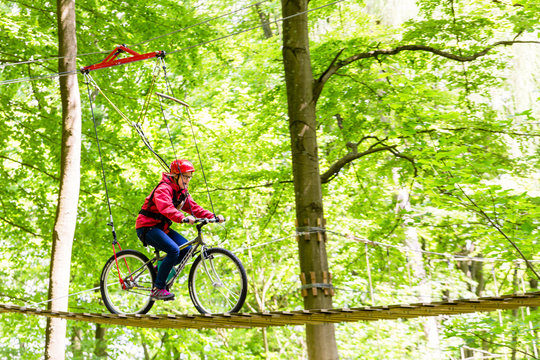 M&auml;dchen f&auml;hrt Fahrrad auf Plattform im Hochseilgarten