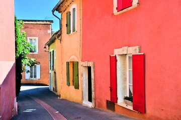 Fototapeta na wymiar Vibrant street in the old town of Rousillon, Provence, France with red and yellow ocher colors