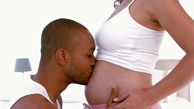 Man kissing his pregnant partners bump