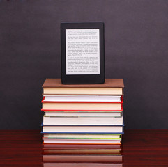 electronic book reader and pile old books on wood desk table