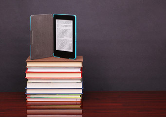 electronic book reader and pile old books on wood desk table