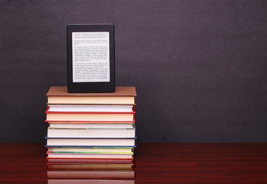 electronic book reader and pile old books on wood desk table