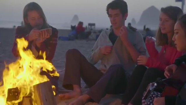 Cute teenage girl takes picture of her friends by the fire