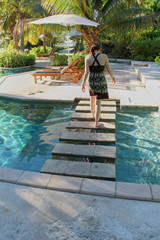 woman walking across steps of pool at island resort in Fiji