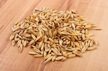 Heap of organic oat grains on wooden table, healthy nutrition