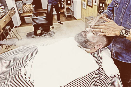 male barber massaging beard.