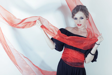 woman in black dress with red sash on light background
