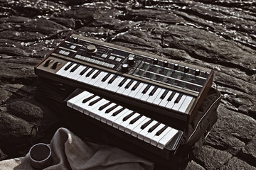 Music synthesizer lying on rocks close up - obrazy, fototapety, plakaty
