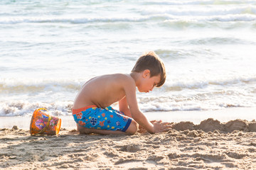 Bambino che gioca sulla spiaggia e mare mosso sullo sfondo