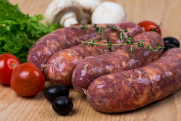uncooked raw sausages on wooden board