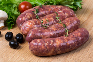 uncooked raw sausages on wooden board