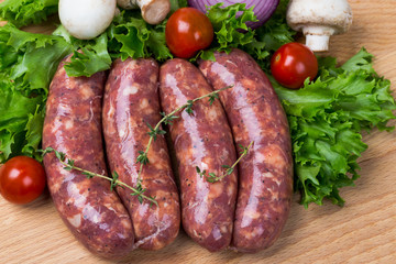 uncooked raw sausages on wooden board