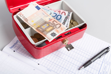 Geldkassette, Bargeld und ein Kassenbuch für Einnahmen und Ausgaben eines Unternehmers