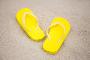 Fototapeta na wymiar close up of flip flops on sandy beach