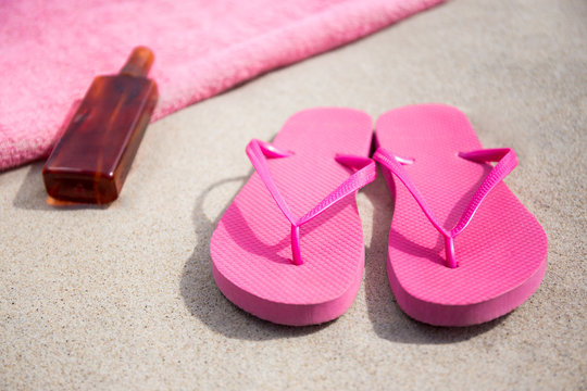 summer concept - flip flops, towel and suntan lotion bottle on s