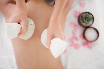 Pretty woman enjoying a herbal compress massage